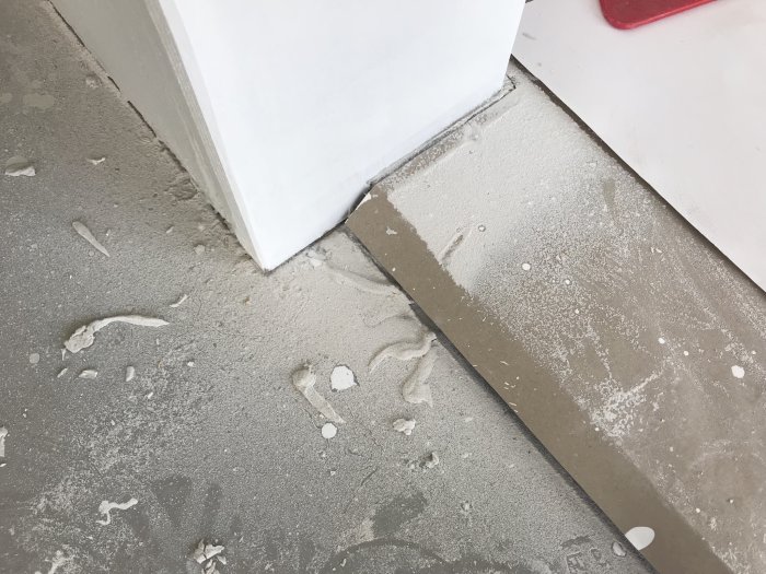Renoveringsdamm nära golvsockel och köksstomme utan plastskydd.