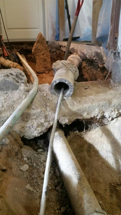 Elkabel går genom ett dörrhål och över en betongsula under renovering.