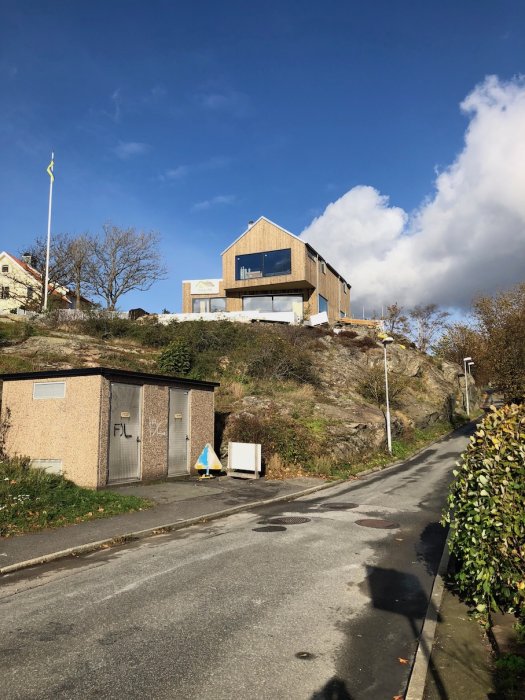 Modernt hus under konstruktion med synligt arbete på övre våningen och en klarblå himmel i bakgrunden.