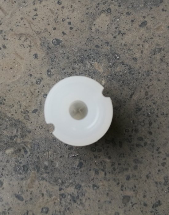 Vit plugg på marmorerad grå yta, ca 12mm höjd och 10mm diameter.