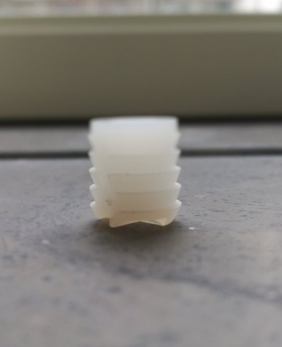 Vit plastplugg på köksbänk, cirka 12mm hög och 10mm bred.