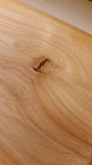 En närbild på en kvist i körsbärsträ, ungefär lika stor som en 50-öring, inbäddad i träets ådring.