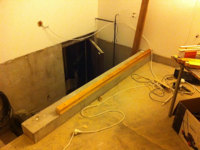 Bild på underkonstruktion av en spaljé nära en källartrappa i en verkstad med verktyg och byggmaterial utspridda.