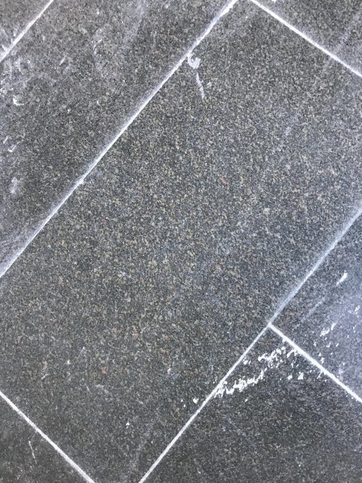 Granitplattor med spår av gipsdamm, i olika grå nyanser och mörka fläckar.
