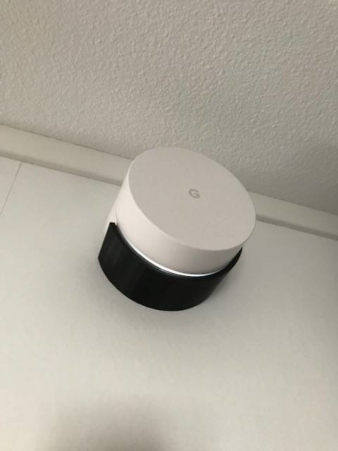 Google WiFi-enhet monterad i en vit hållare på vägg.