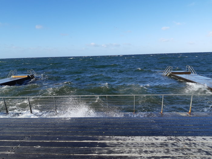 Havsvågor slår mot kajen och bryggor under blåsig dag i Malmö.