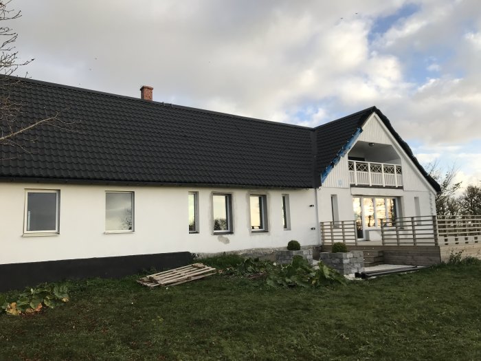 Nyrenoverat hus med ett nyklart svart tegeltak, vita väggar och en skorsten.