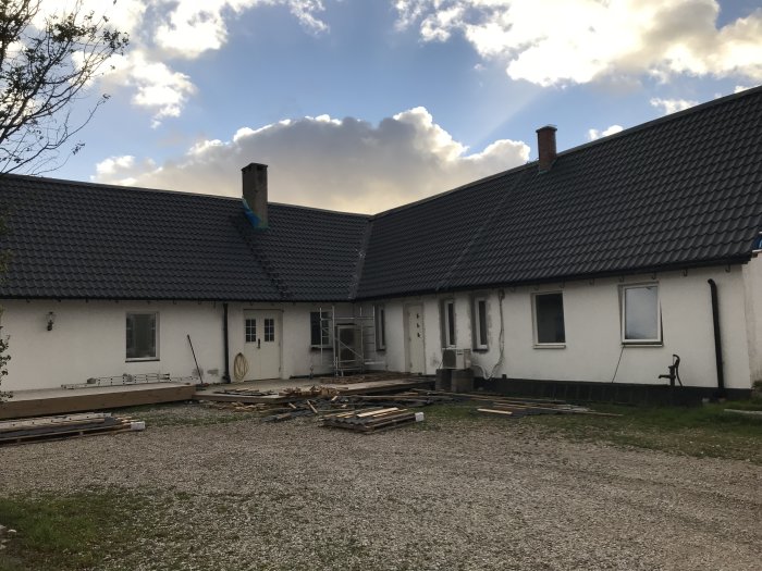 Renoverat hus med nylagt tak och byggmaterial på marken, arbete med takkupan nästa.