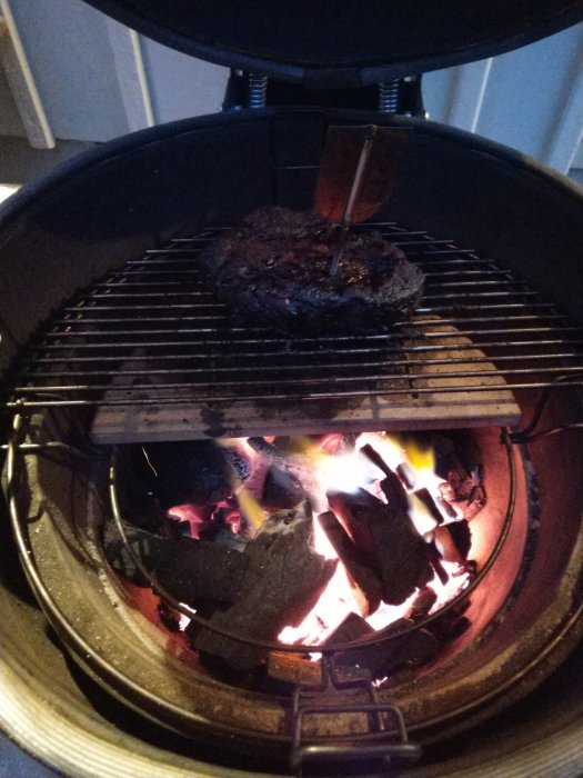 Stekande kött på grill över glödande träkol utan tändvätska.