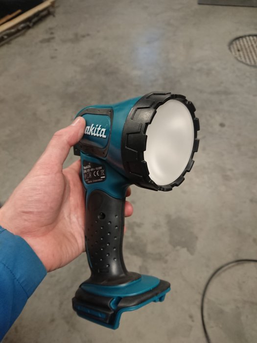 Hand som håller en Makita 18V handlampa med frostat ljusinsats, efter modifiering för ett mjukare ljus.