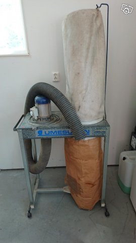 Umesugen dammavskiljare med en sliten filtersäck och en stor papperspåse kopplad via flexibel slang.