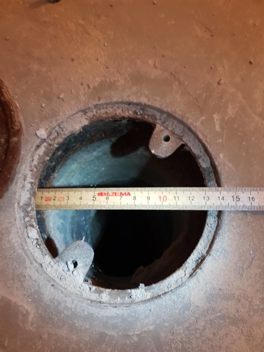 Öppet golvhål med ett måttband som visar diametern, tänkt för installation av ny golvbrunn.