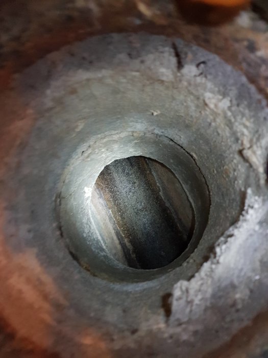 Närgränsfoto av en avloppsöppning i betonggolv, planerad position för ny golvbrunn i renoverad tvättstuga.