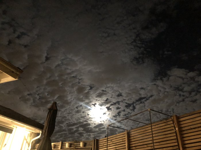 Mörk natt med delvis molnig himmel och månen som lyser fram bakom molnen.