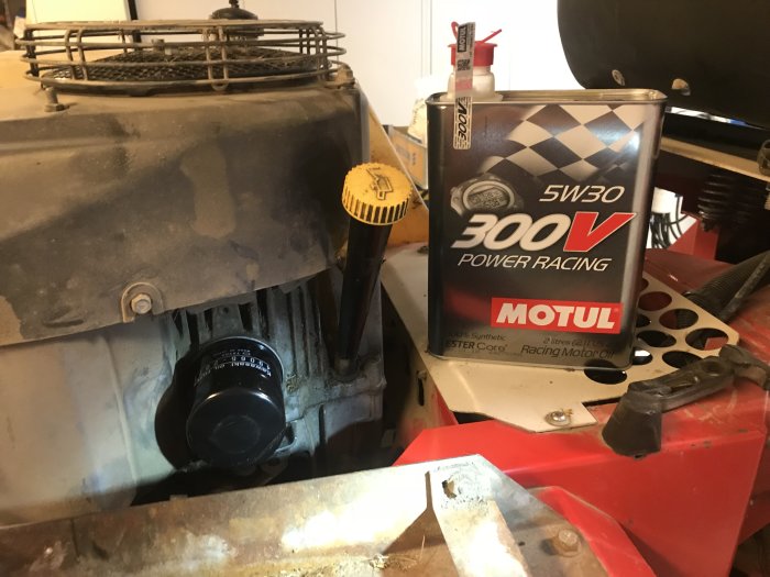 Motor och burk med syntetolja 5W30 från Motul på ett stökigt arbetsbord.