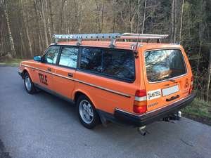 En orange Volvo 245 kombi parkerad utomhus med "Tele" text och stege på taket.