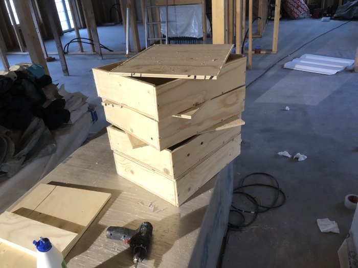 Handgjorda backboxar av plywood med borr och konstruktionstillbehör på en byggarbetsplats.