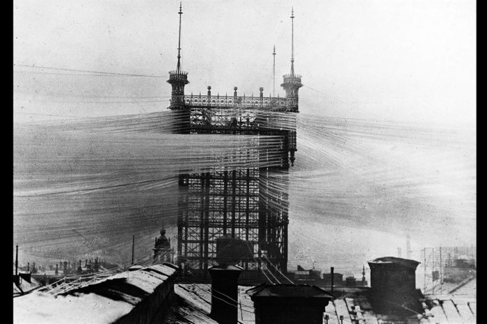 Svartvit bild av det historiska Telefontornet i Stockholm med många telefonledningar.