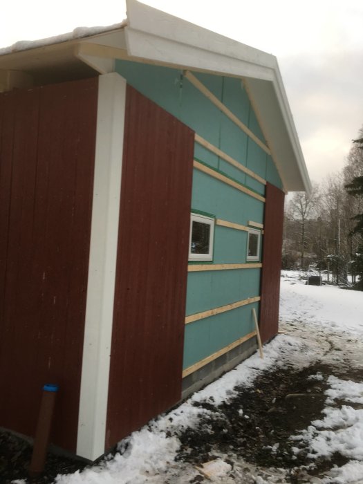 Nyinstallerad panel på ett garage med snötäckt tak och marken omkring.