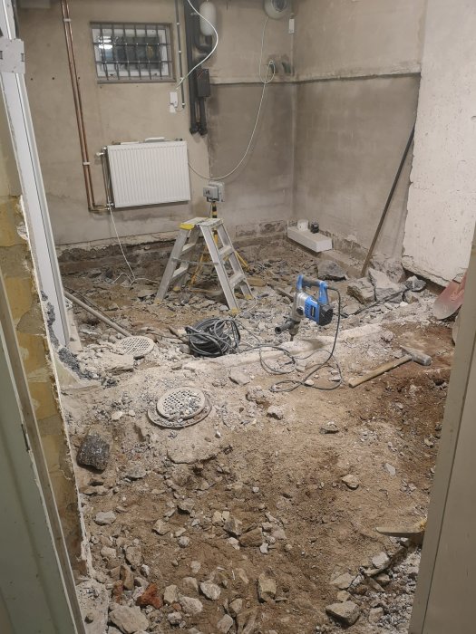 Rivningsarbete i källarutrymme med spillror, en stege, radiator och kanalfläkt till höger.