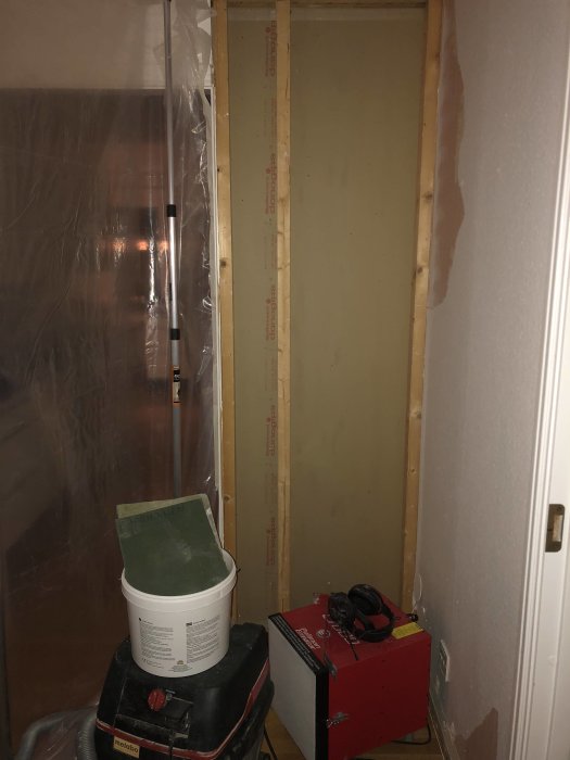 Renoveringsarbete med borttaget gips, en luftrenare och byggdammsugare i ett rum.