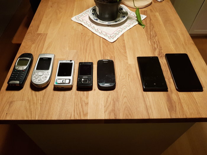 Samling av äldre Nokia-mobiler på ett bord med ett tomt utrymme för en saknad N8-modell.