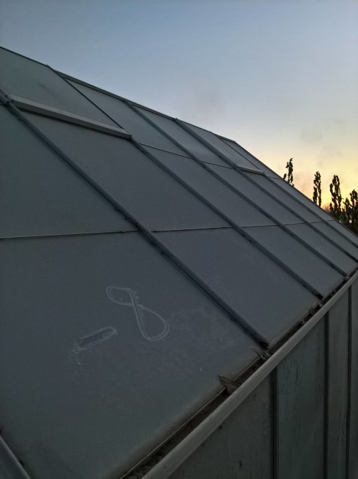 Frostdrabbat växthus vid skymning med frosttecken avsatta på glastaket.