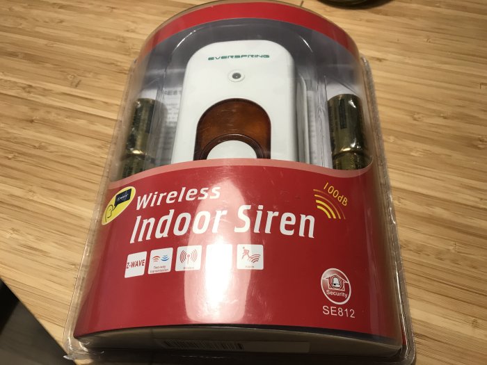 Oöppnad Everspring SE812 inomhussiren i förpackning på träbord, betecknad med "Wireless Indoor Siren".