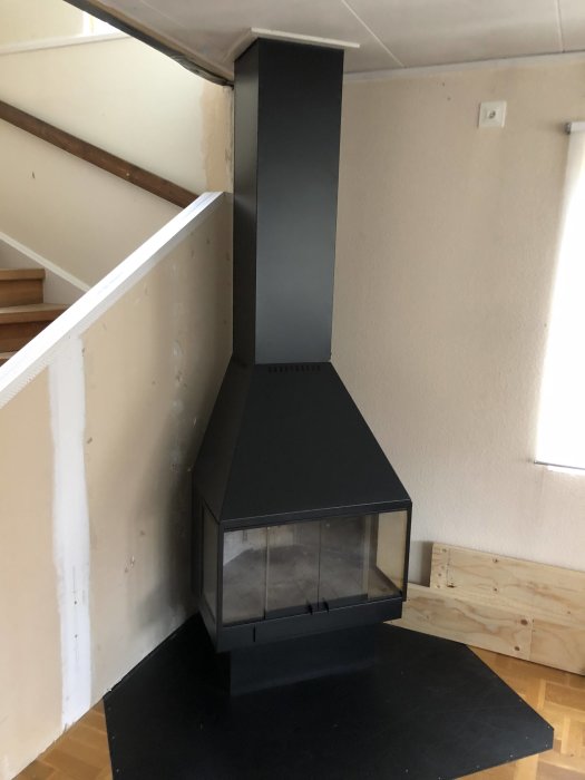 Modern hörnkamin installerad i ett renoverat rum med synliga områden för ytterligare väggfix.