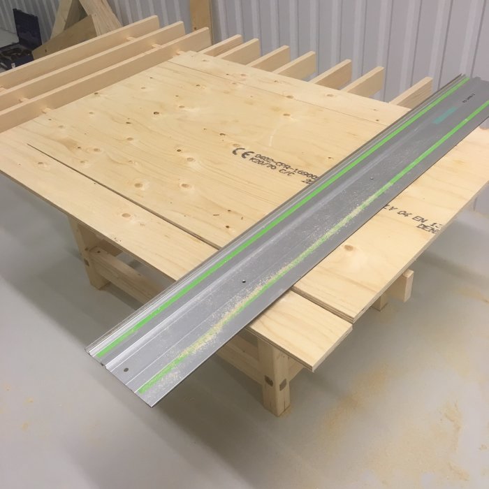 Halvfärdigt trähyllprojekt med skruvade hyllplan upplagda på en arbetsbänk, verktygsspår synliga.