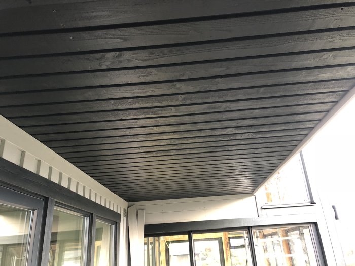 Nyinstallerad mörk panel under takutskjut vid ett uterum.
