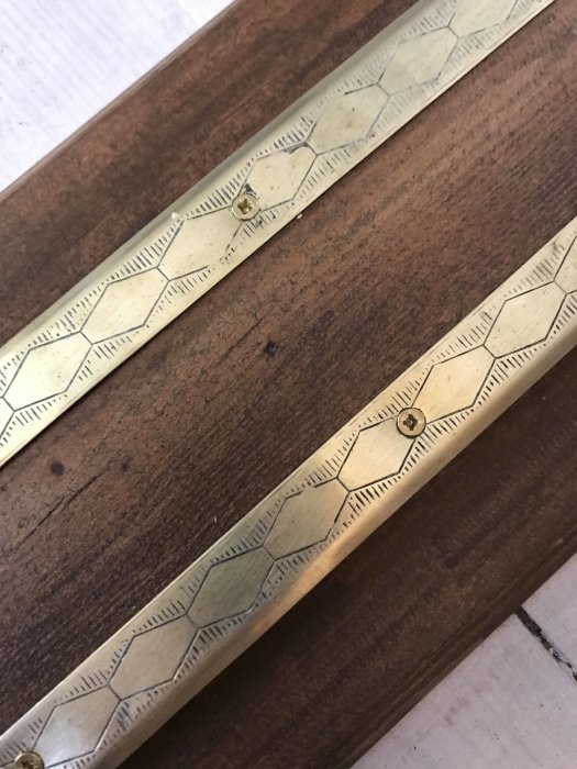 Nyligen uppolerad tröskellist i trä med inlagda dekorativa metallplattor.