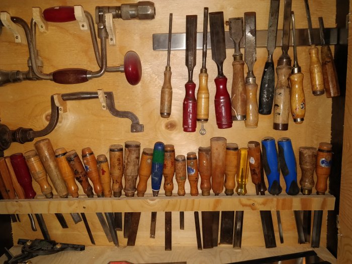 Verktygshylla med diverse handhyvlar, stämjärn och andra snickeriverktyg upphängda ordentligt.