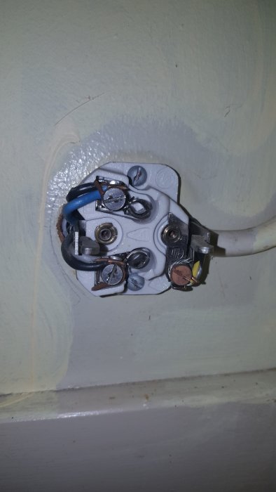 Öppet eluttag med synliga kablar och anslutningar, inklusive jordkabel, i ett äldre hus.