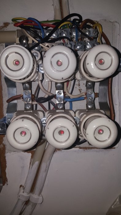 Gammalt eluttag med ojordade kablar och keramiska plintar i en elcentral.