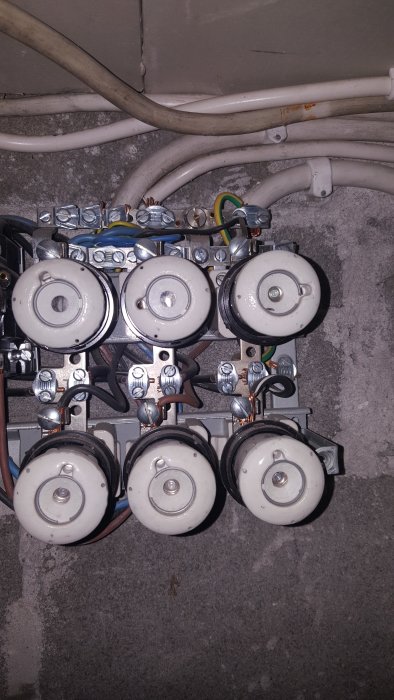 Elskåpsinteriör med säkringar och kablar, tecken på ålder i installationen, ingen synlig jordning.