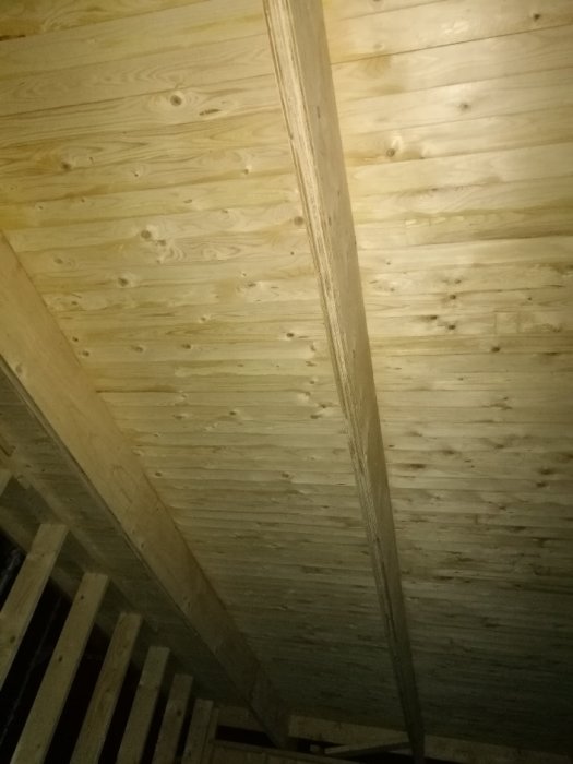 Tak konstruerat med egentillverkade balkar av plywood under råspont i ett pågående husbygge.