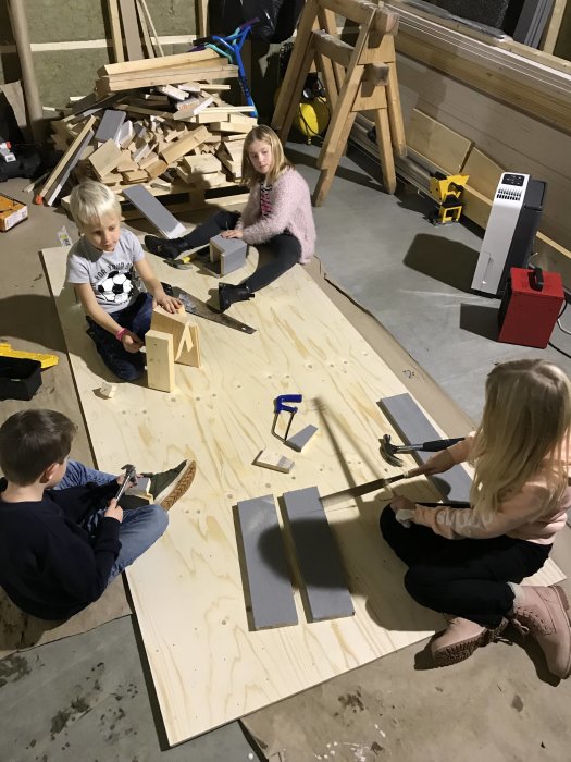 Barn använder handverktyg för träarbete i ett nyisolerat hemmasnickeri.