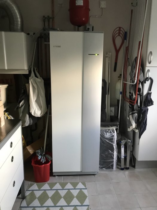 Värmepump på klinkergolv i förrådsutrymme med röda gummifötter och extra dämpning.