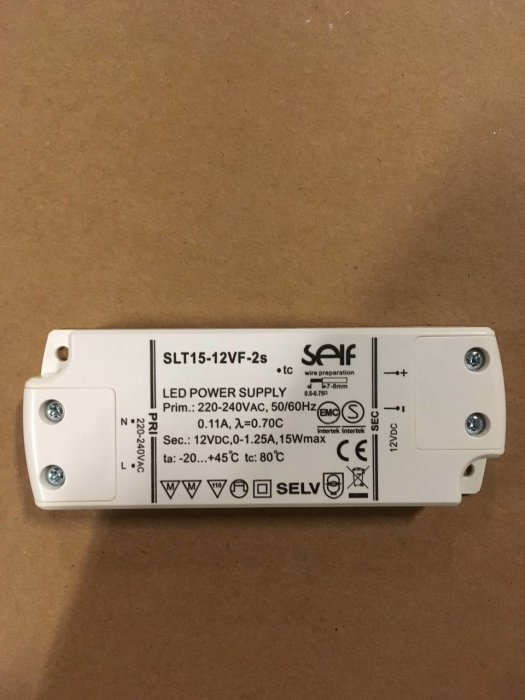 LED-drivdon märkt med SLT15-12VF-2s från INR för 220-240VAC på en kartongbakgrund.