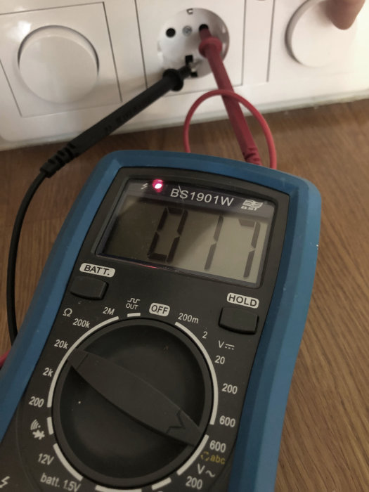 Multimeter visar 0 V när testproberna är anslutna till ett vägguttag, vilket indikerar problem med elektriciteten.