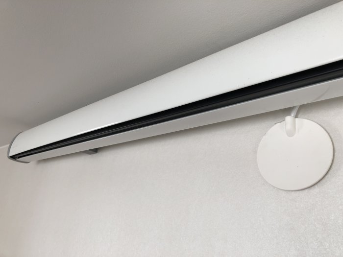 Kabel går in i vägg via en rund, vit kabeldosa, under en vit fönsterbräda mot en ljus vägg.