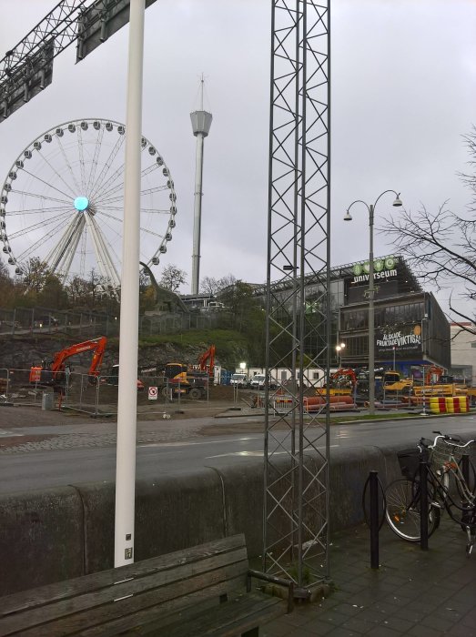 Grå mulen dag i stad med utsikt över pariserhjul, byggarbetsplats och universum.