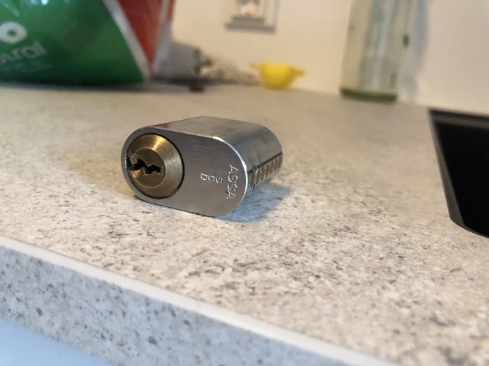 Låscylinder av märket ASSA på köksbänk inför byte i altandörr.