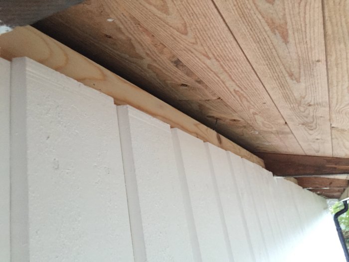 Glespanel installerad mellan takstolar med gap för ventilation ovanför panelkanten på husets insida.
