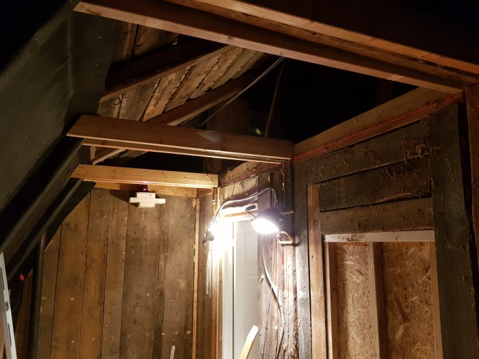 Inomhusbygge med synliga träbjälkar och laserstråle längs väggen för att markera räta linjer.