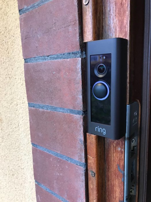 Ring Videodoorbell installerad på trä och tegel vid en dörrkarm.