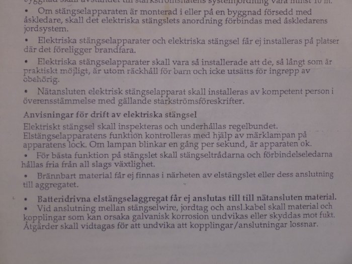 Fotografi av en del av en bruksanvisning för elstängsel med instruktioner och säkerhetsinformation.