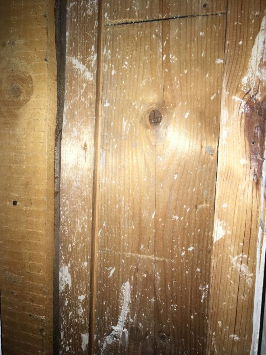 Grov gammal trävägg med synliga reglar och plankor, eventuellt från en garderob under rivning.