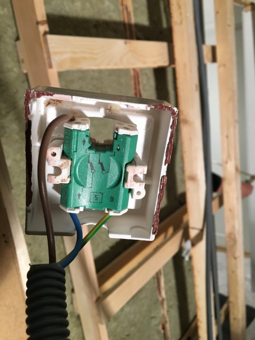 Eluttag med osammanlänkade kablar i en väggkonstruktion under installation.